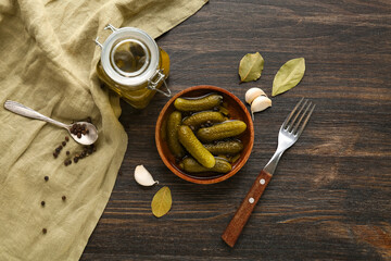 Bowl and jar with tasty canned cucumbers on wooden background