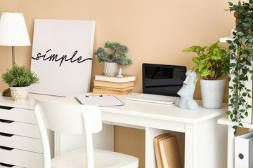 Fototapeta premium Blank laptop with books and plants on table in office