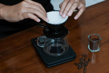 Closeup of a hand prepare filter paper on dripper to brew coffee v60, making coffee homemade.