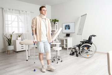 Injured young man after accident with crutches in clinic