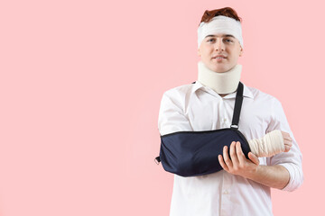 Injured young man after accident with broken arm on pink background