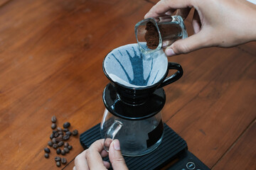 Closeup of a hand Prepares a brewing coffee V60 With pouring Freshly Ground Coffee at dripper filter, making coffee homemade.