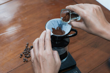 Closeup of a hand Prepares a brewing coffee V60 With pouring Freshly Ground Coffee at dripper...