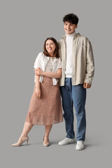 Young beautiful couple in stylish clothes on grey background