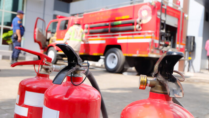 Naklejka premium Red Fire Extinguishers with Blurred Firetruck in Background