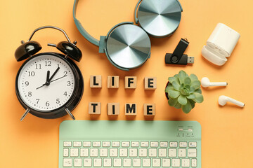 Cubes with text LIFE TIME, alarm clock and keyboard on orange background. Top view