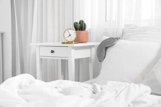 Alarm clock with cactus on table in light bedroom