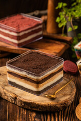 chocolate tiramisu rainbow cake in a small box, there is also a red velvet rainbow cake behind it