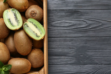 Box with fresh kiwi and mint on black wooden background