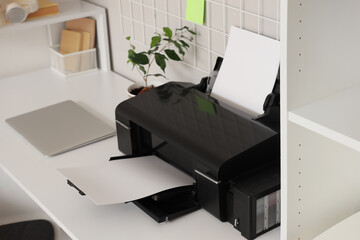 Modern printer with laptop on desk in light office, closeup
