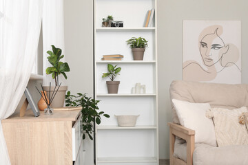 Interior of modern living room with shelving unit, sofa and chest of drawers
