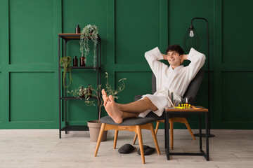 Handsome young happy man with different tools and fresh pedicure sitting at home