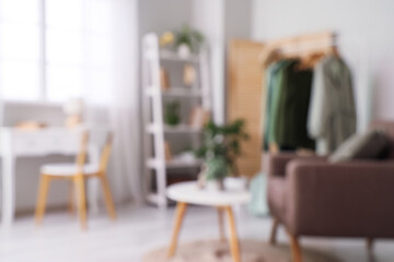 Blurred view of dressing room with clothes rack, armchair and table
