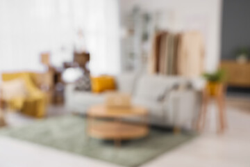 Blurred view of living room with clothes rack, sofa and laptop on table