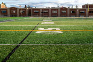 Obraz premium Synthetic turf football 50 yard line, block number, in white along with black lacrosse line and yellow soccer mid field line 