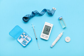 Glucometer with lancet pen, insulin and pills on blue background. Diabetes concept