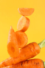 Whole and cut fresh carrots on orange background, closeup