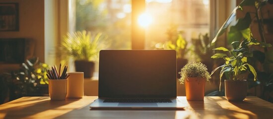 Fototapeta premium Laptop on a wooden desk in a bright room with a window and plants.