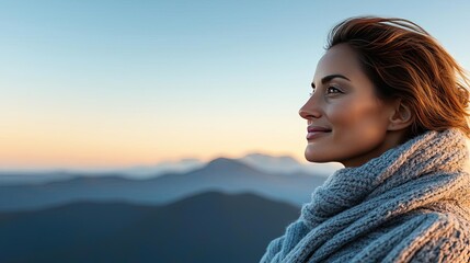 Fototapeta premium Woman in a warm scarf enjoying a peaceful moment in the mountains at sunset.