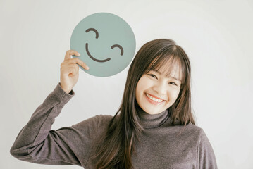 Happy young Asian woman holding smile emoji face, positive mental health, world mental health day...