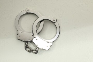 Classic chain handcuffs on white table, top view. Space for text