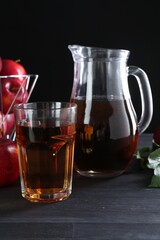 Tasty fresh apple juice and fruits on black wooden table