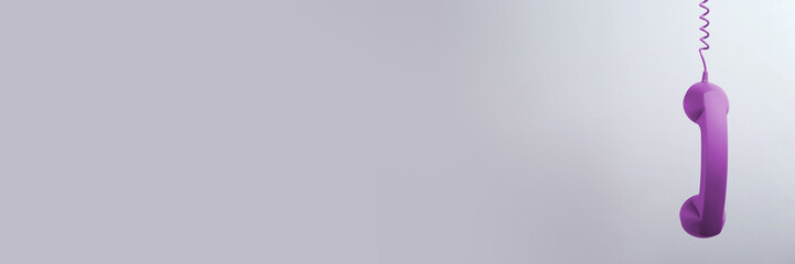 Purple corded telephone handset on grey background. Banner design with space for text