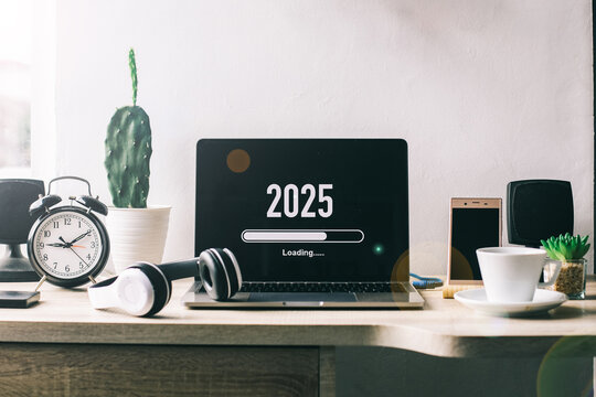 Office desk with 2025 loading bar on laptop screen for happy new year concept