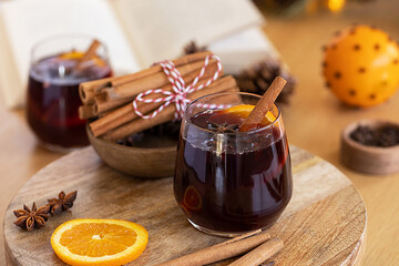 A glass of warming mulled wine on the table and a book. A cozy autumn scene.