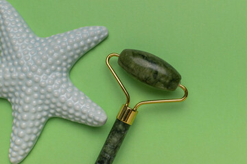 Green Jade Roller and Starfish on Trendy Green Background