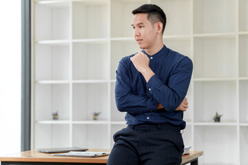 A thoughtful man in a blue shirt sits pensively in a modern office space with minimalist design features.