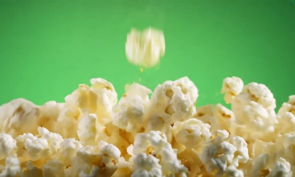 Falling popcorn kernels isolated against a green screen backdrop