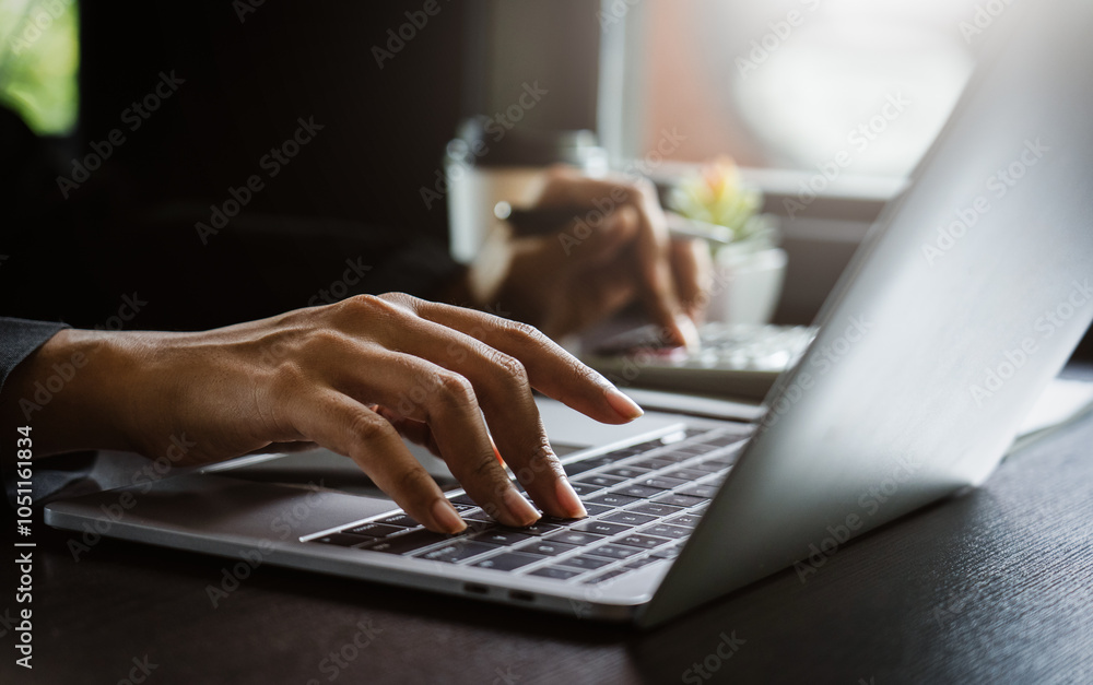Poster close-up of hands typing on a laptop keyboard while working remotely in an office setting, emphasizi