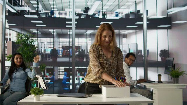 Employee at the new job starting her first day and meeting colleagues, feeling proud of the opportunity and unpacking her belongings at the corporate workstation. Getting hired. Camera B.