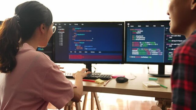 Slow motion back end software developer engineer for computer programming working together on debugging writing computing code, solving complex algorithms display on monitor in office. Burgeoning