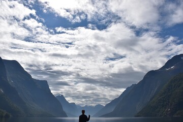 Fototapeta premium Norwegian Fjord with huge mountains and person standing in front 