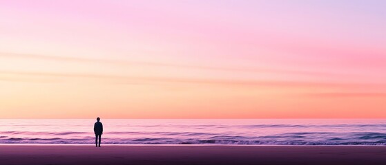 Fototapeta premium A solitary figure standing on a tranquil beach at sunset, surrounded by beautiful pastel skies reflecting over calm waters.