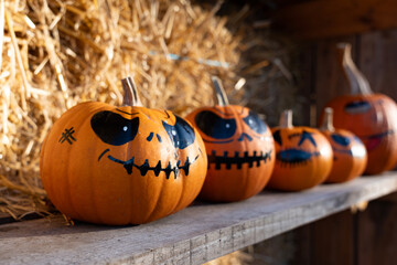 Festively decorated Halloween pumpkins with hand-painted scary faces, displayed in an outdoor farm setting, showcasing the autumn spirit, creativity, and seasonal celebration of the holiday