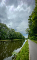 Obraz premium A serene riverbank with vibrant trees, fluffy clouds, and lush greenery is ideal for naturethemed activities