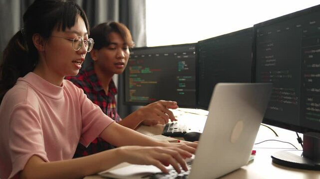 Slow motion back end software developer engineer for computer programming working together on debugging writing computing code, solving complex algorithms display on monitor in office. Burgeoning