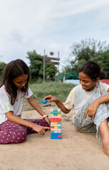Candid indian girls playing wooden stack board game outdoors