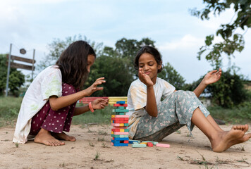Barefoot indian friends playing stack wooden game in a park