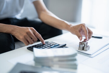 Obraz premium Saving money. Man calculate finances home pay bills taxes savings economy financial at home and saving money stacking coins with calculator
