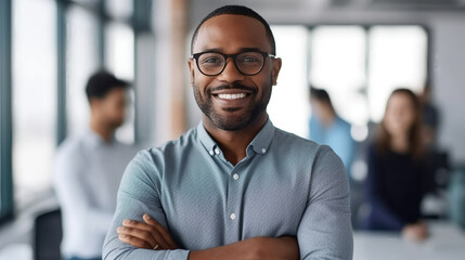 Fototapeta premium Portrait of a smiling business leader standing in a modern office with arms crossed, looking at the camera.