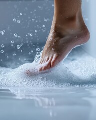 Fototapeta premium A close-up of a foot stepping into a bubble-filled bath with droplets of water splashing around.