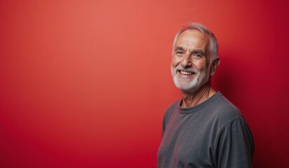 Fototapeta premium Cheerful Senior Man Smiling Against Vibrant Red Background with Copy Space