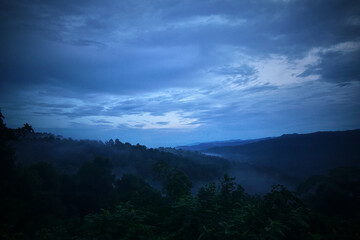 The sky is dark and cloudy, with a misty fog covering the mountains