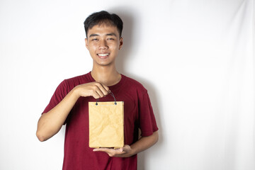 Asian teenager smiling sincerely while holding a cardboard bag