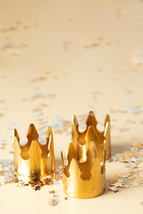 Epiphany Day or Dia de Reyes Magos concept. Three gold crowns on beige background with star sparkling confetti