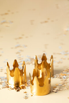 Epiphany Day or Dia de Reyes Magos concept. Three gold crowns on beige background with star sparkling confetti